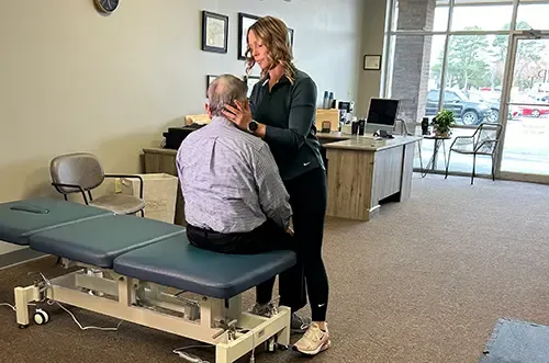 Physical therapist treating a seated patient’s neck and shoulders